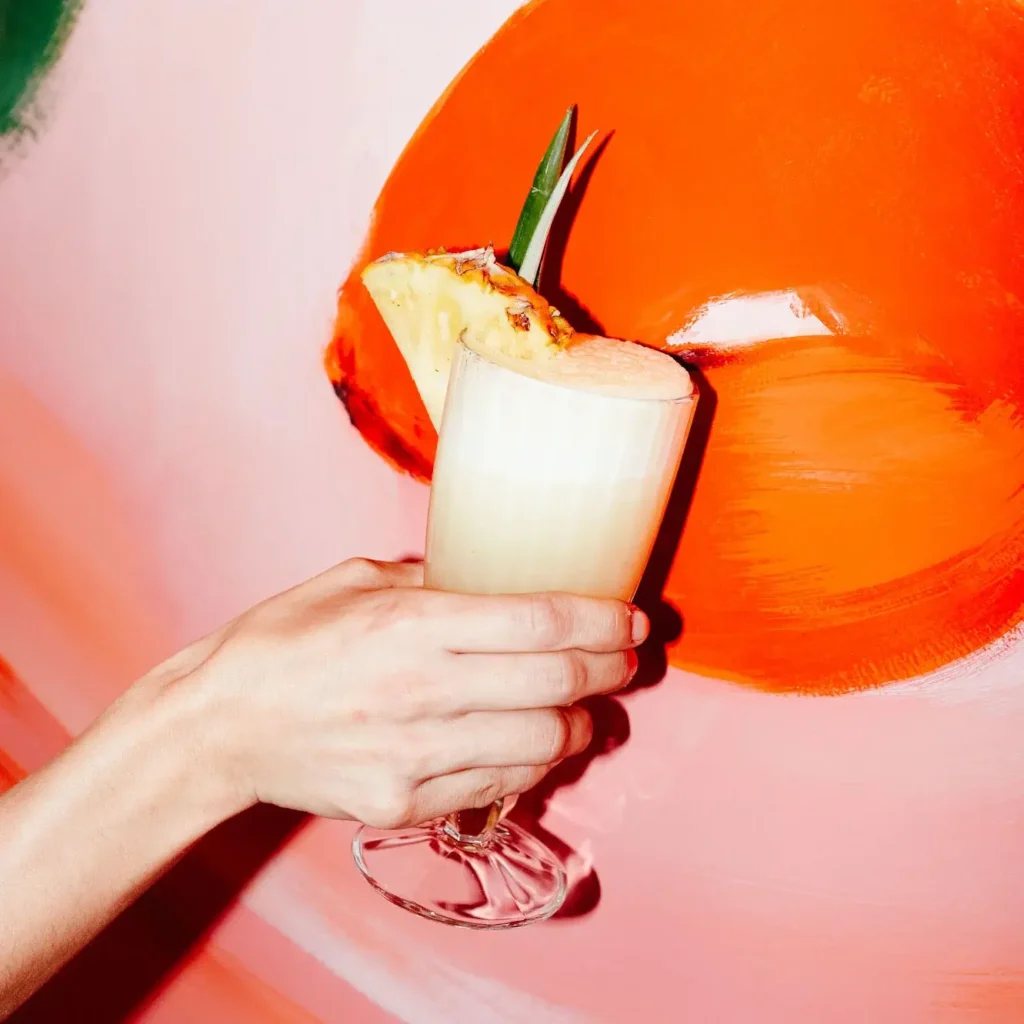 Personne tenant un cocktail Pina Colada